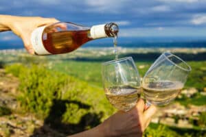 pouring white wine into two glasses in-hand with a view